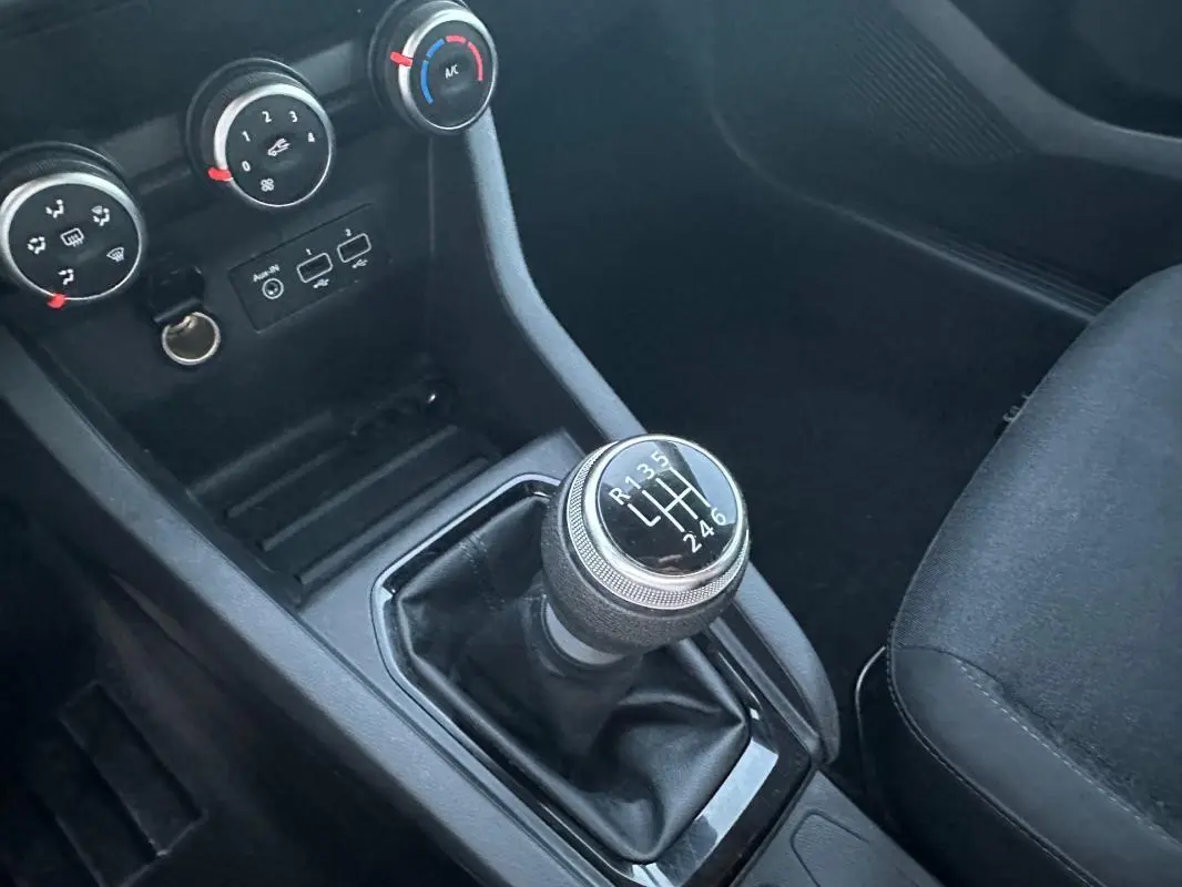 Gros plan sur le levier de vitesses manuel et la console centrale noire de la Renault Clio gris foncé 2022.