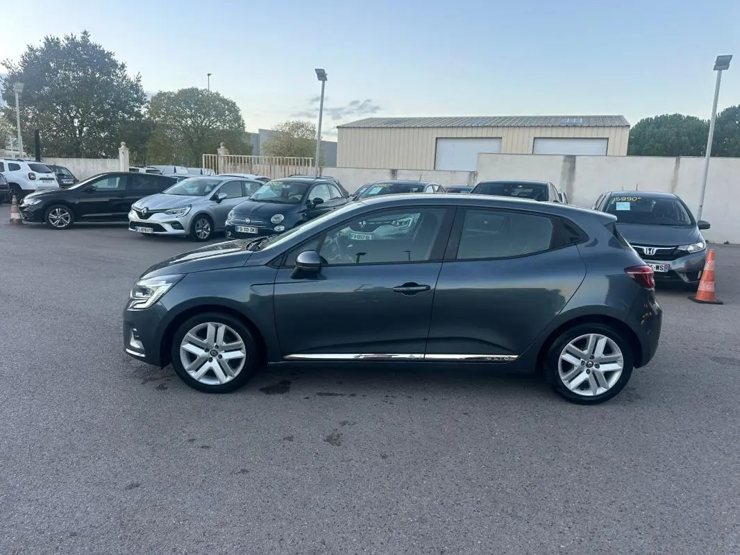 Profil côté gauche d'une Renault Clio gris foncé 2022 V TCe 90 Business, stationnée sur un parking extérieur.