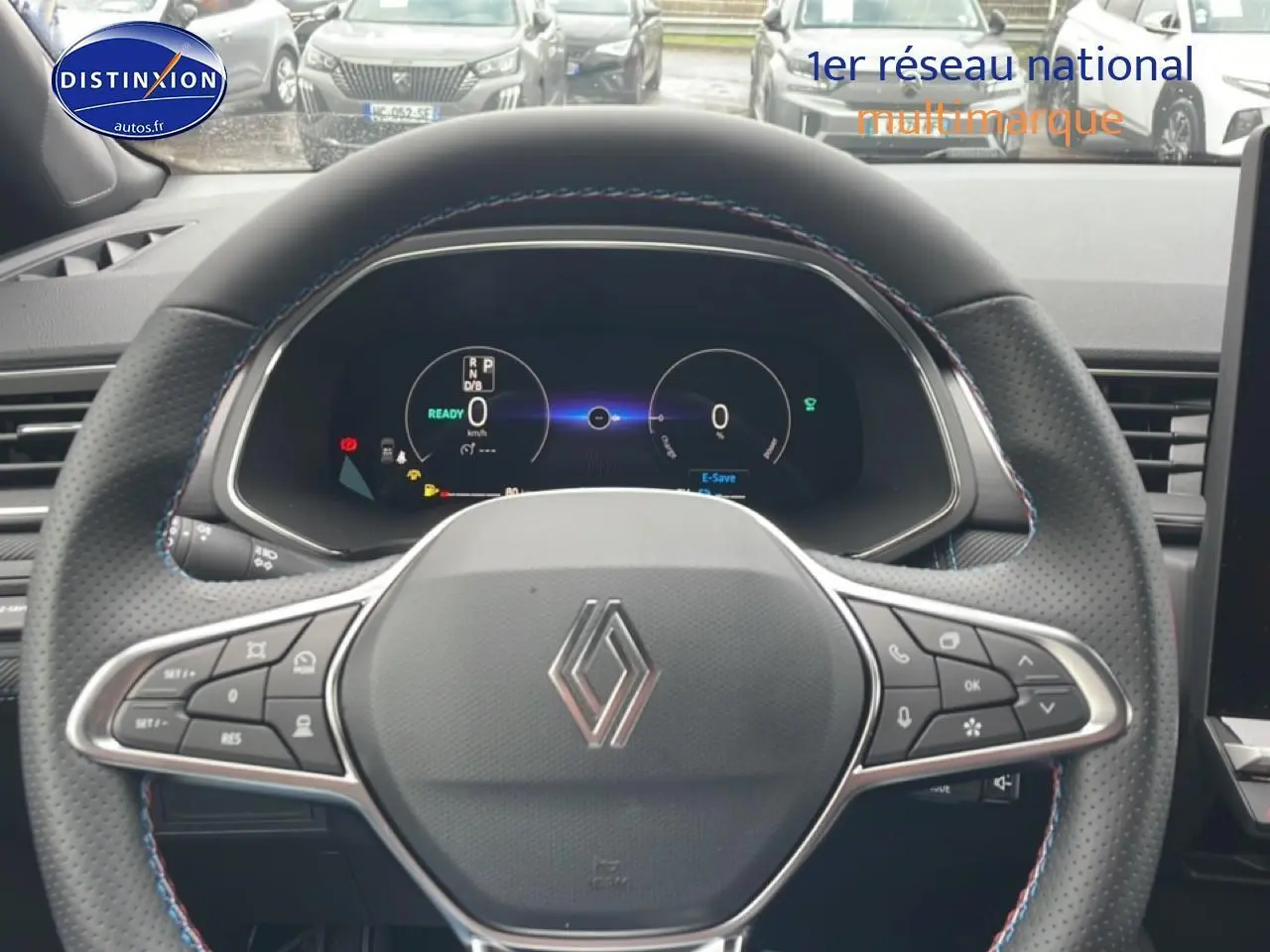 Vue rapprochée du volant cuir perforé avec logo Renault et tableau de bord numérique du Captur gris cassiopée 2025.