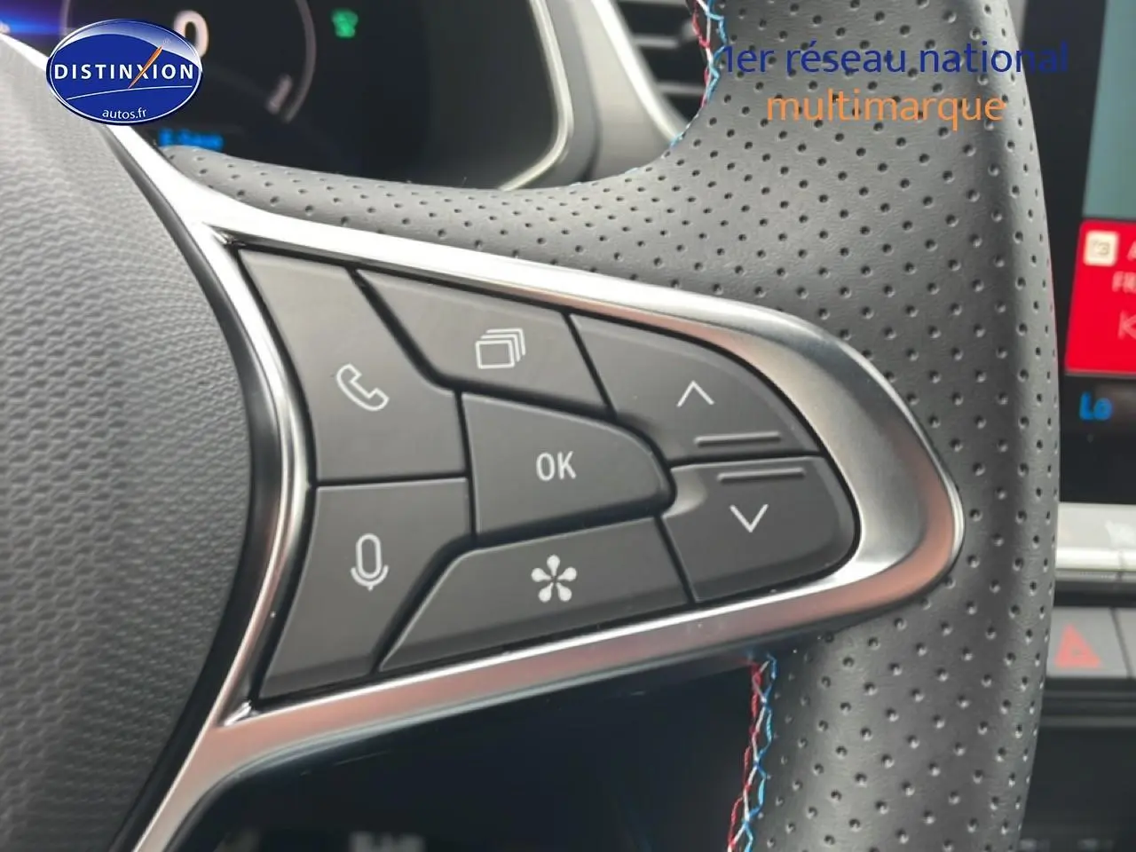 Gros plan sur les commandes multifonctions côté gauche du volant cuir perforé du Renault Captur gris cassiopée.