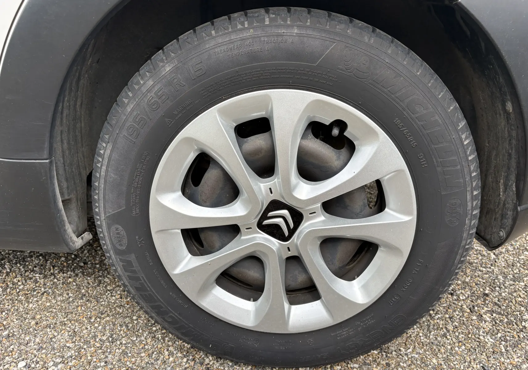 Gros plan sur la roue avant gauche d'une Citroën C3 blanche de 2019 avec jante en alliage et logo Citroën central.