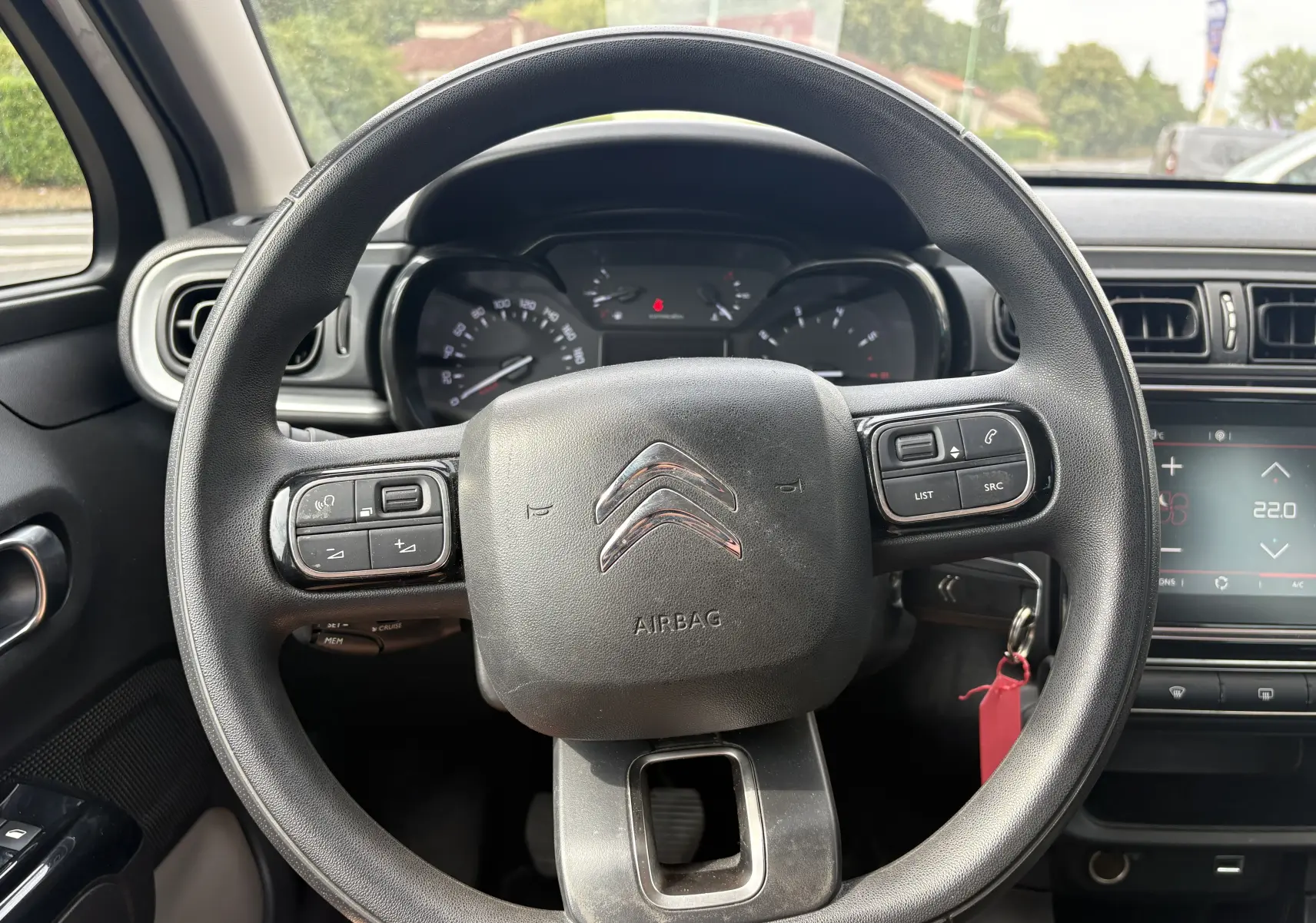 Vue rapprochée du volant noir de la Citroën C3 blanche 2019, avec commandes intégrées et tableau de bord en arrière-plan.