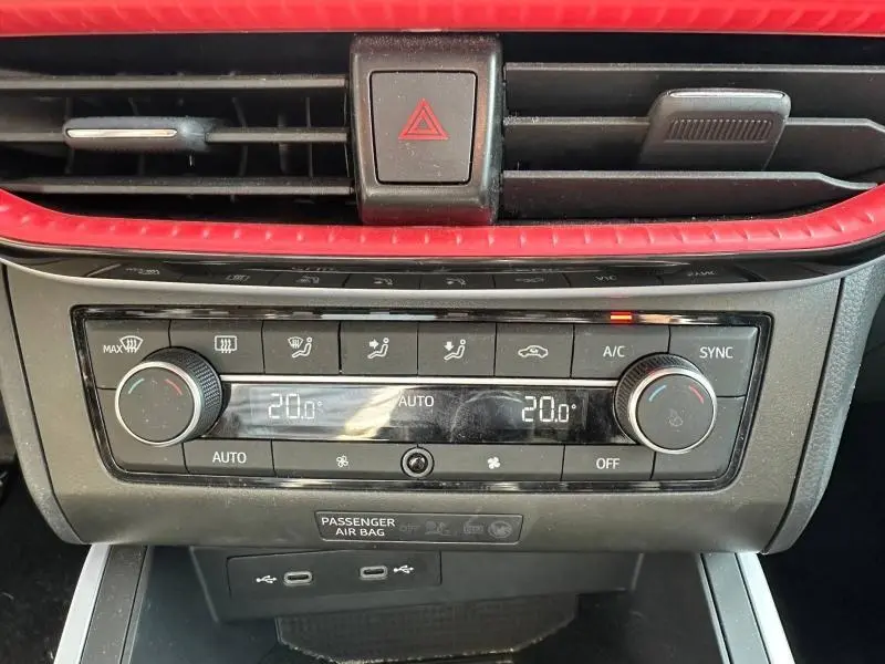 Vue rapprochée de la console centrale du SEAT Arona 2025, avec commandes climatisation et bandeau rouge décoratif.