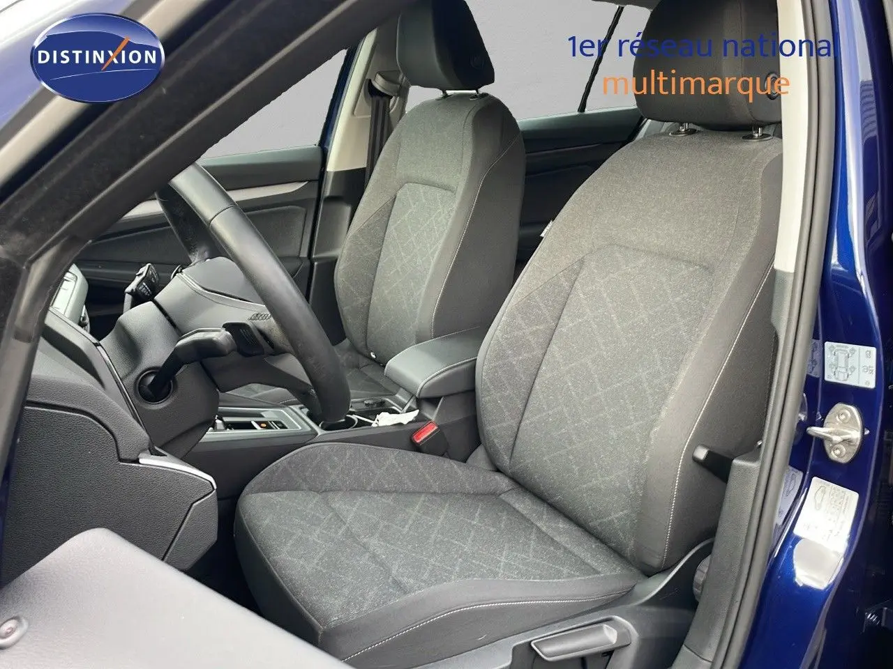 Vue intérieure côté gauche montrant les sièges tissu gris et le volant d'une Volkswagen Golf VIII bleu lapiz metal 2023.