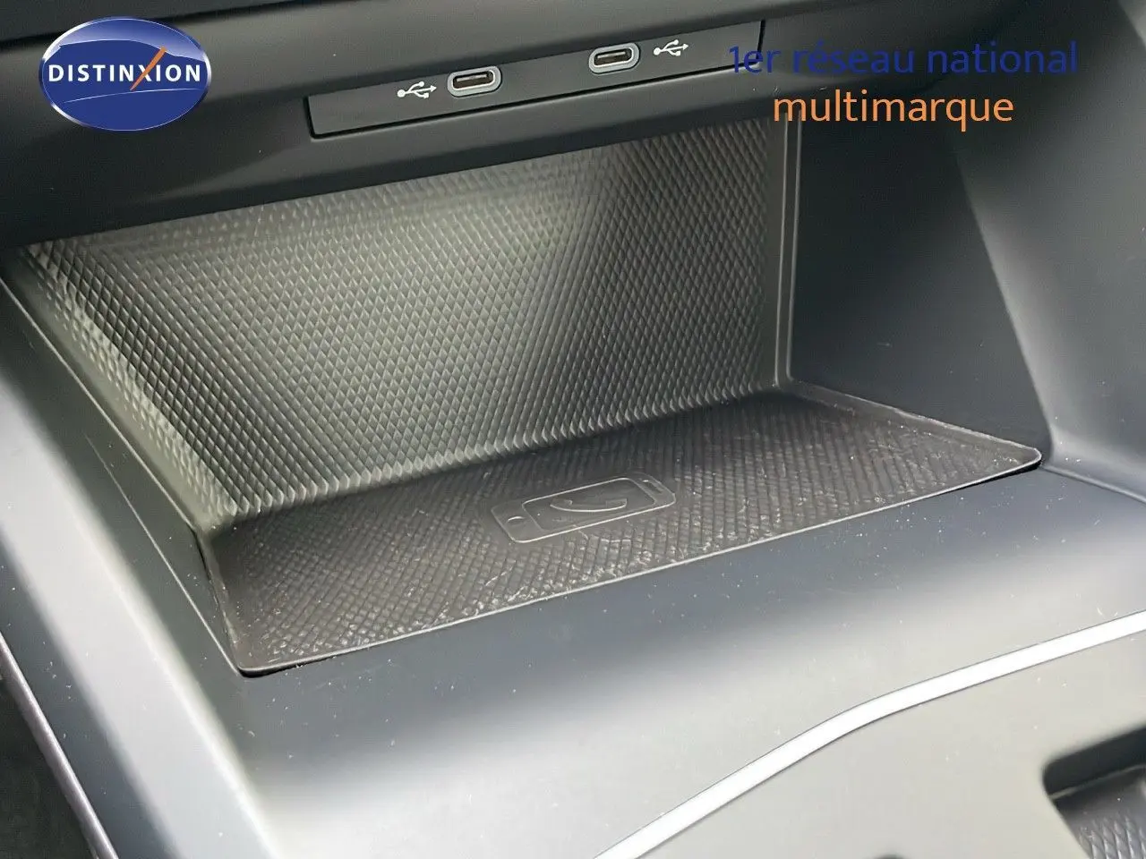 Gros plan sur la console centrale avec zone de recharge sans fil et ports USB d'une Volkswagen Golf VIII bleu lapiz metal.