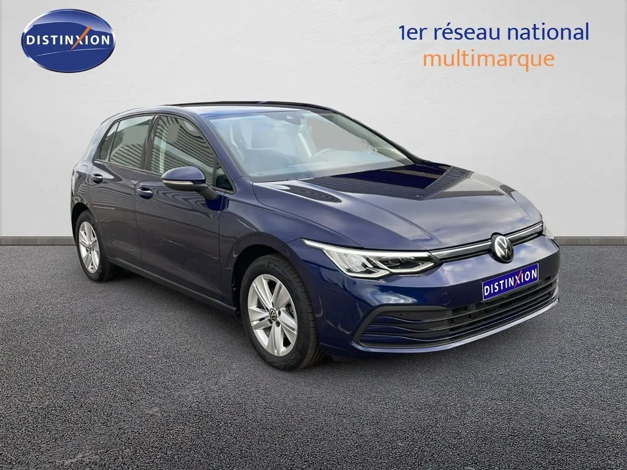 Volkswagen Golf VIII bleu lapiz metal en 3/4 avant droit, avec jantes alliage et phares LED allumés.