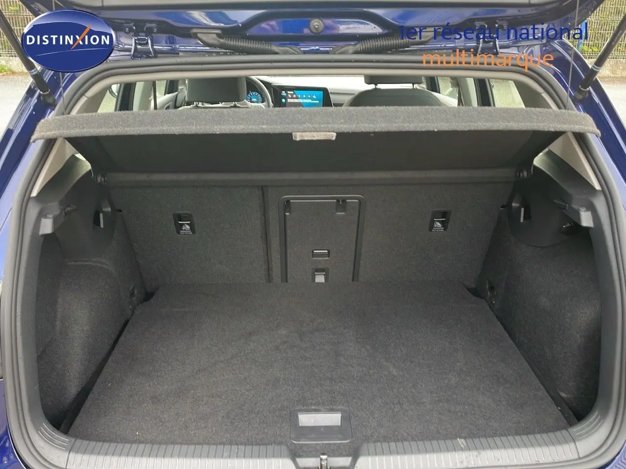 Coffre ouvert d'une Volkswagen Golf VIII bleu lapiz metal, vue arrière montrant l'espace de chargement vide et la tablette cache-bagages.