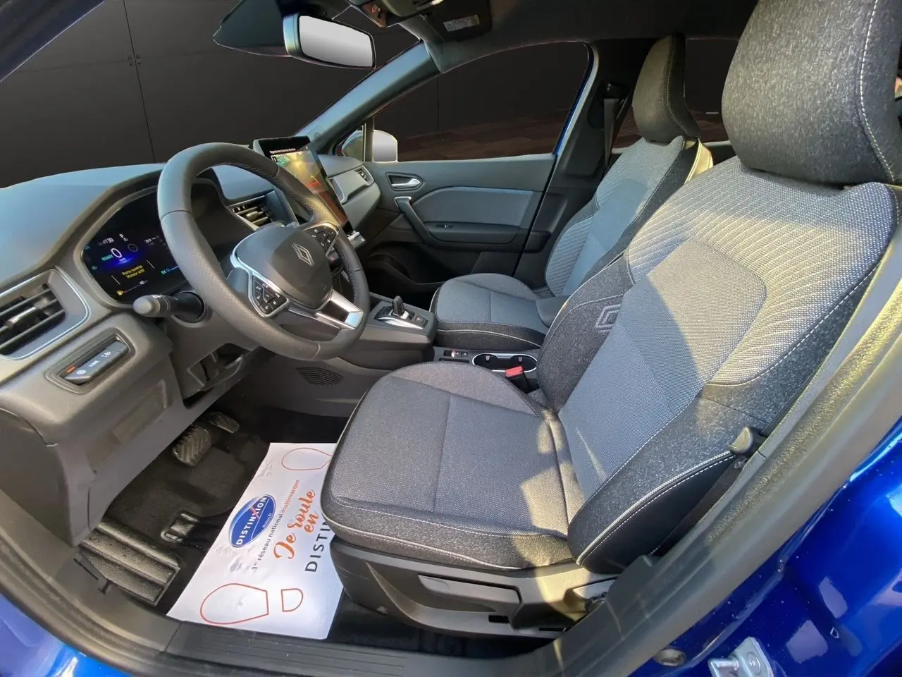 Vue intérieure côté conducteur du Renault Captur 2025 bleu Iron, mettant en valeur les sièges tissu gris et le tableau de bord moderne.