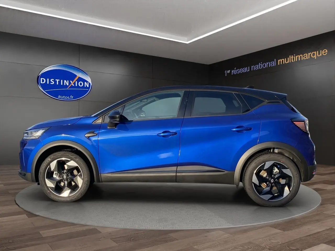 Vue de profil côté gauche du Renault Captur 2025 bleu Iron avec toit noir et jantes distinctives noires et argentées.