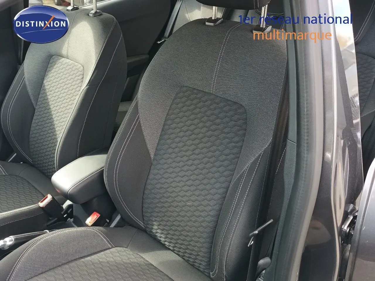 Gros plan sur les sièges avant en tissu gris foncé avec surpiqûres blanches du Ford Puma 2023, porte ouverte côté droit.