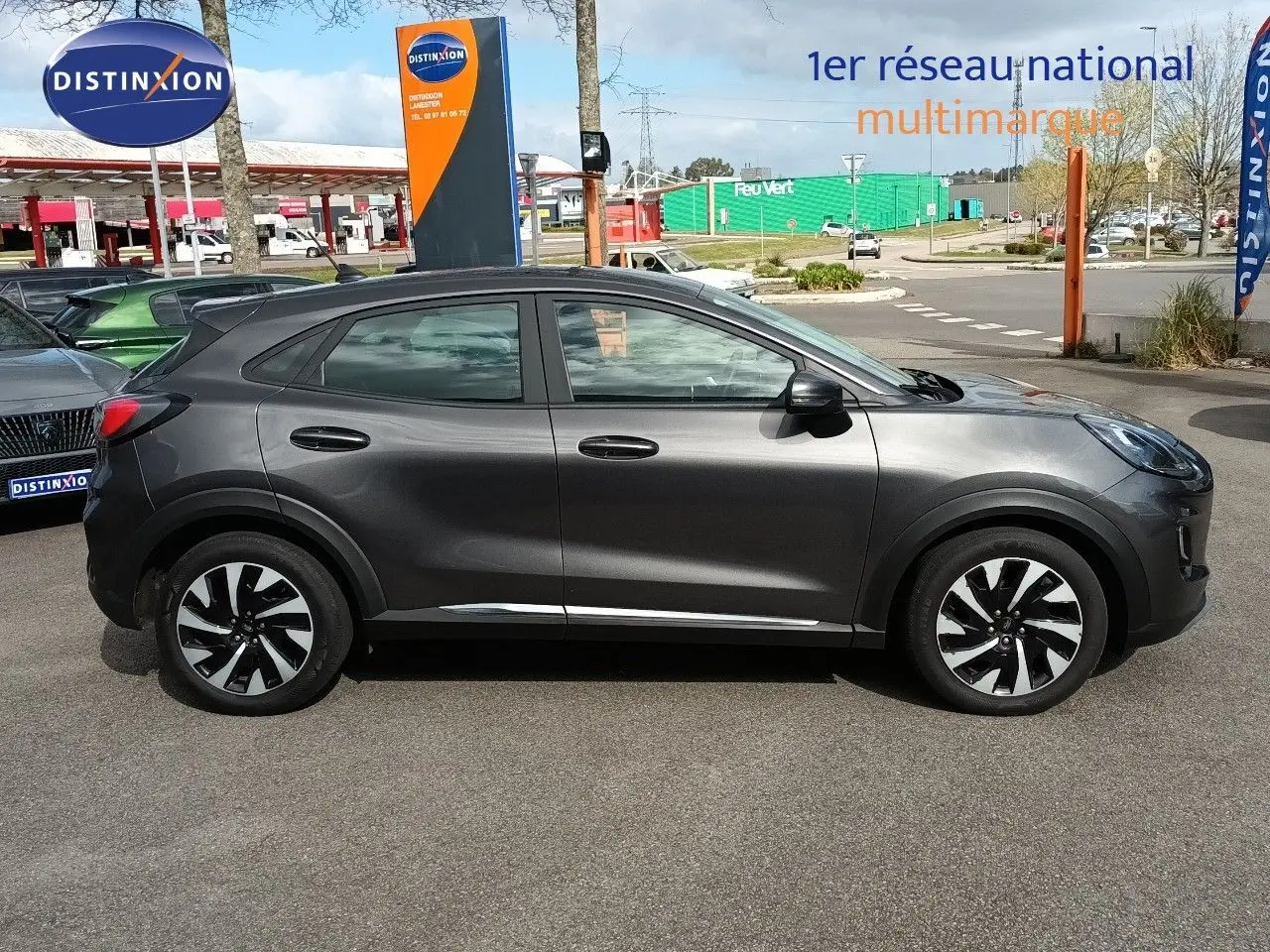 Vue de profil côté gauche d'une Ford Puma gris foncé métal, avec jantes bicolores et détails chromés sous les portes.