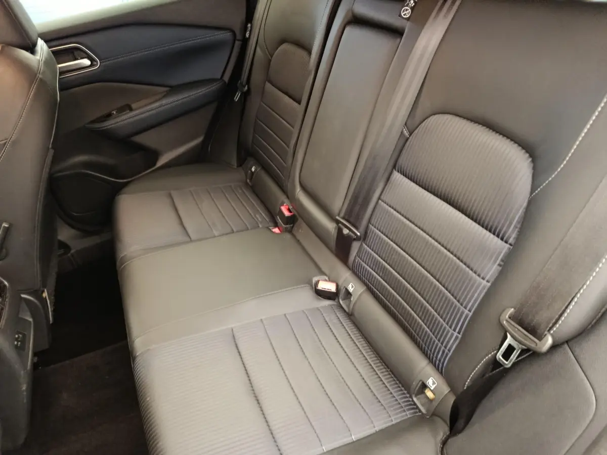 Vue intérieure côté gauche de la banquette arrière noire du Nissan Qashqai 1.3 MHEV Tekna 2023 avec ceintures de sécurité visibles.