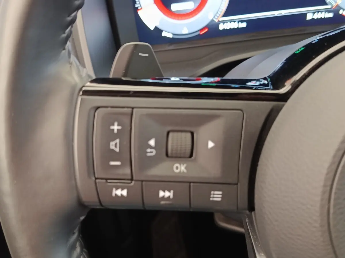 Gros plan sur les commandes au volant du Nissan Qashqai Tekna 2023, avec affichage numérique en arrière-plan.
