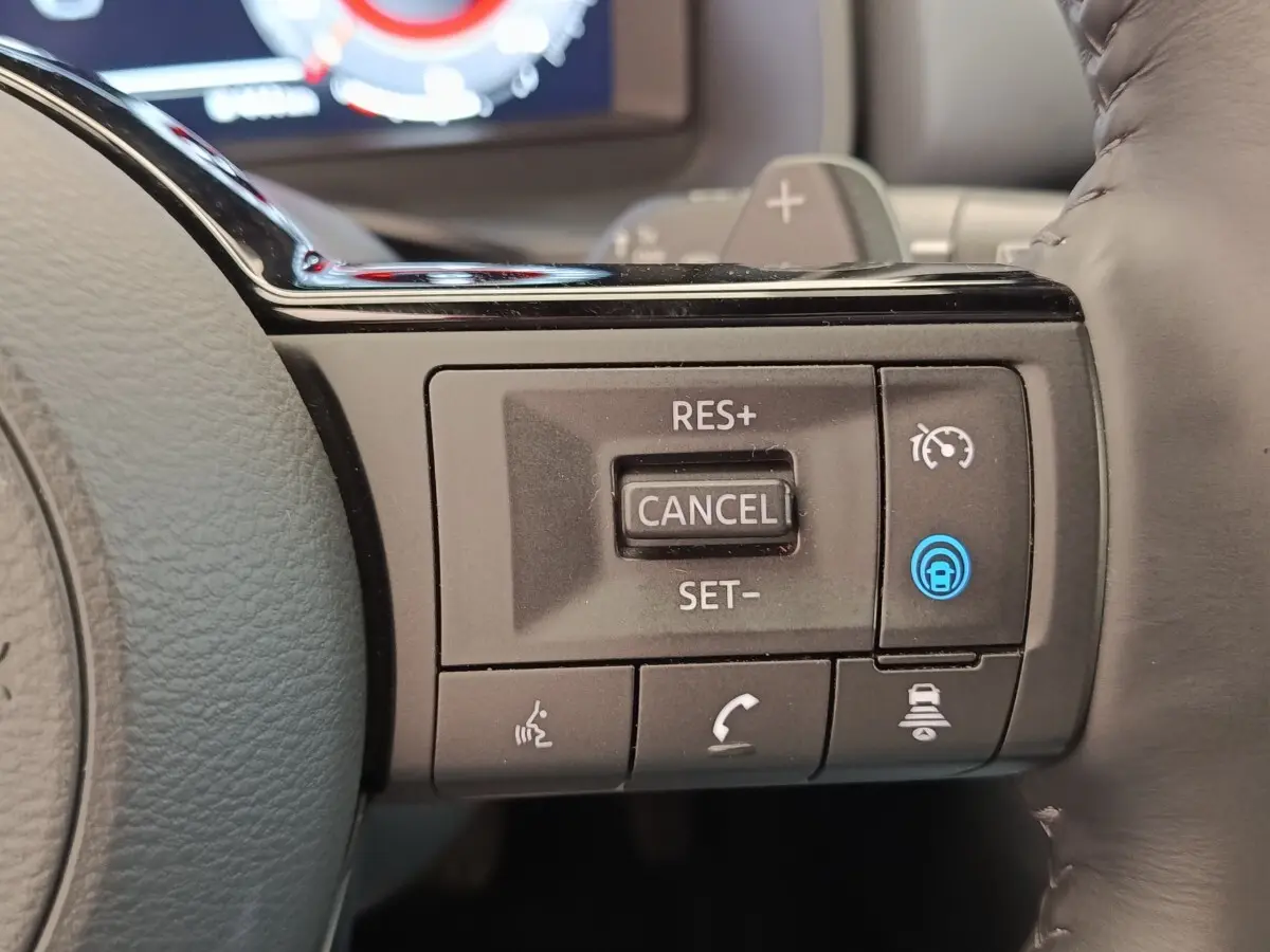 Gros plan sur les commandes de régulateur de vitesse au volant cuir noir du Nissan Qashqai 1.3 MHEV Tekna 2023.