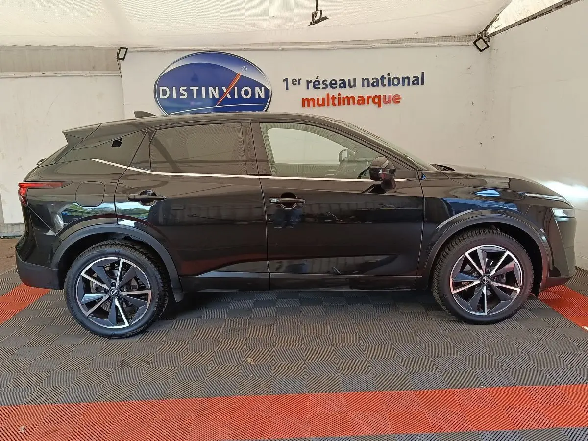 Profil côté gauche du Nissan Qashqai noir 2023, avec jantes alliage et vitres teintées, en intérieur showroom.