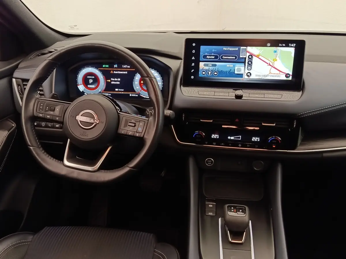 Vue intérieure du tableau de bord noir du Nissan Qashqai 2023 avec écran tactile 12,3 pouces et volant cuir multifonctions.