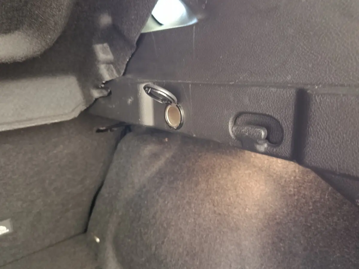 Détail intérieur du coffre du Nissan Qashqai 2023 noir, montrant une prise 12V avec couvercle ouvert.