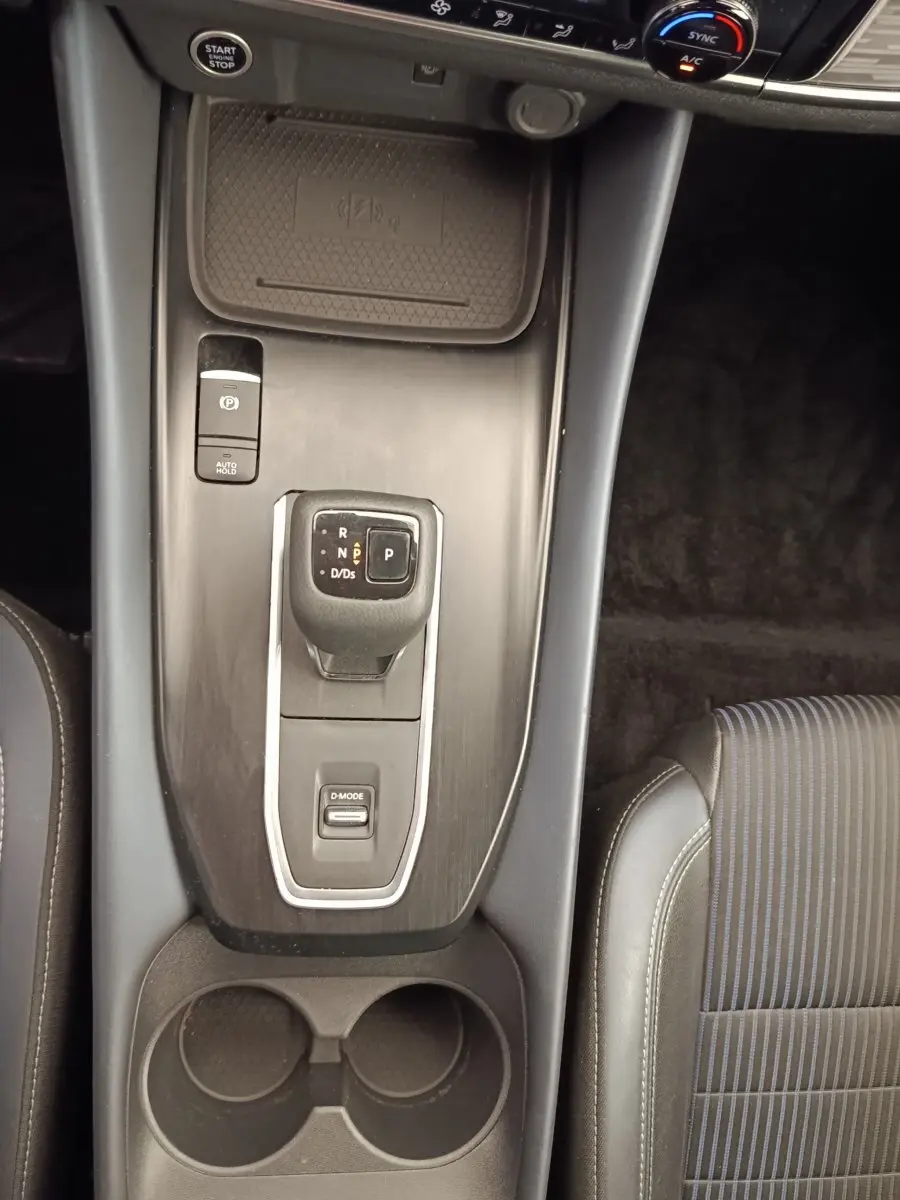 Vue plongeante sur la console centrale noire du Nissan Qashqai 2023, avec levier de vitesses automatique et porte-gobelets.