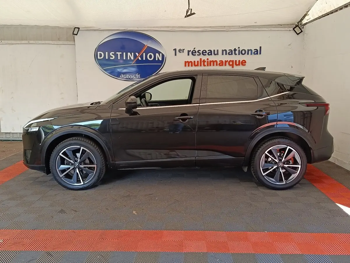 Nissan Qashqai noir vue de profil côté gauche, avec jantes alliage et toit noir brillant dans un showroom.