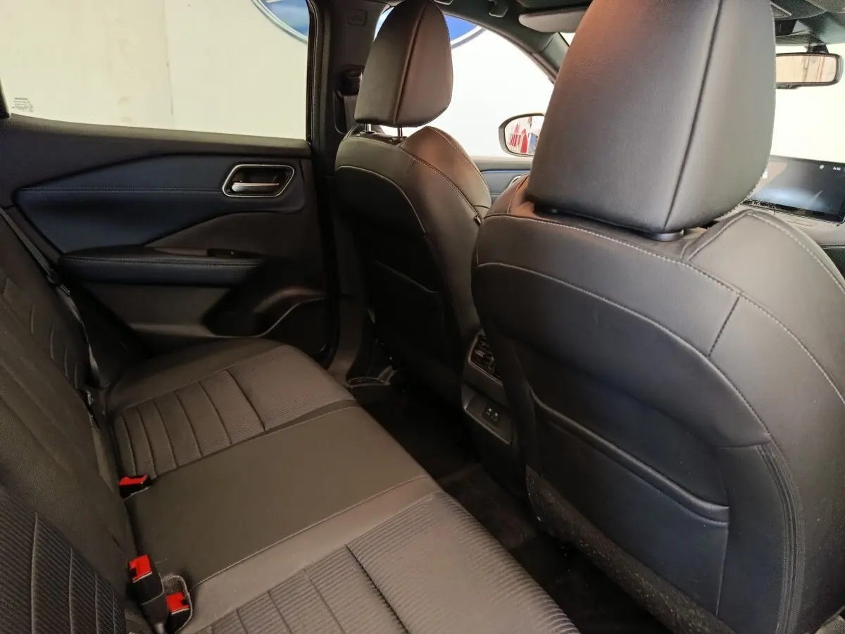 Vue intérieure arrière côté gauche du Nissan Qashqai noir 2023, montrant les sièges en cuir et la console centrale.