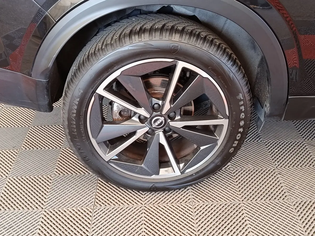 Gros plan sur la roue avant droite noire du Nissan Qashqai 2023 avec jante alliage bicolore et pneu Firestone.