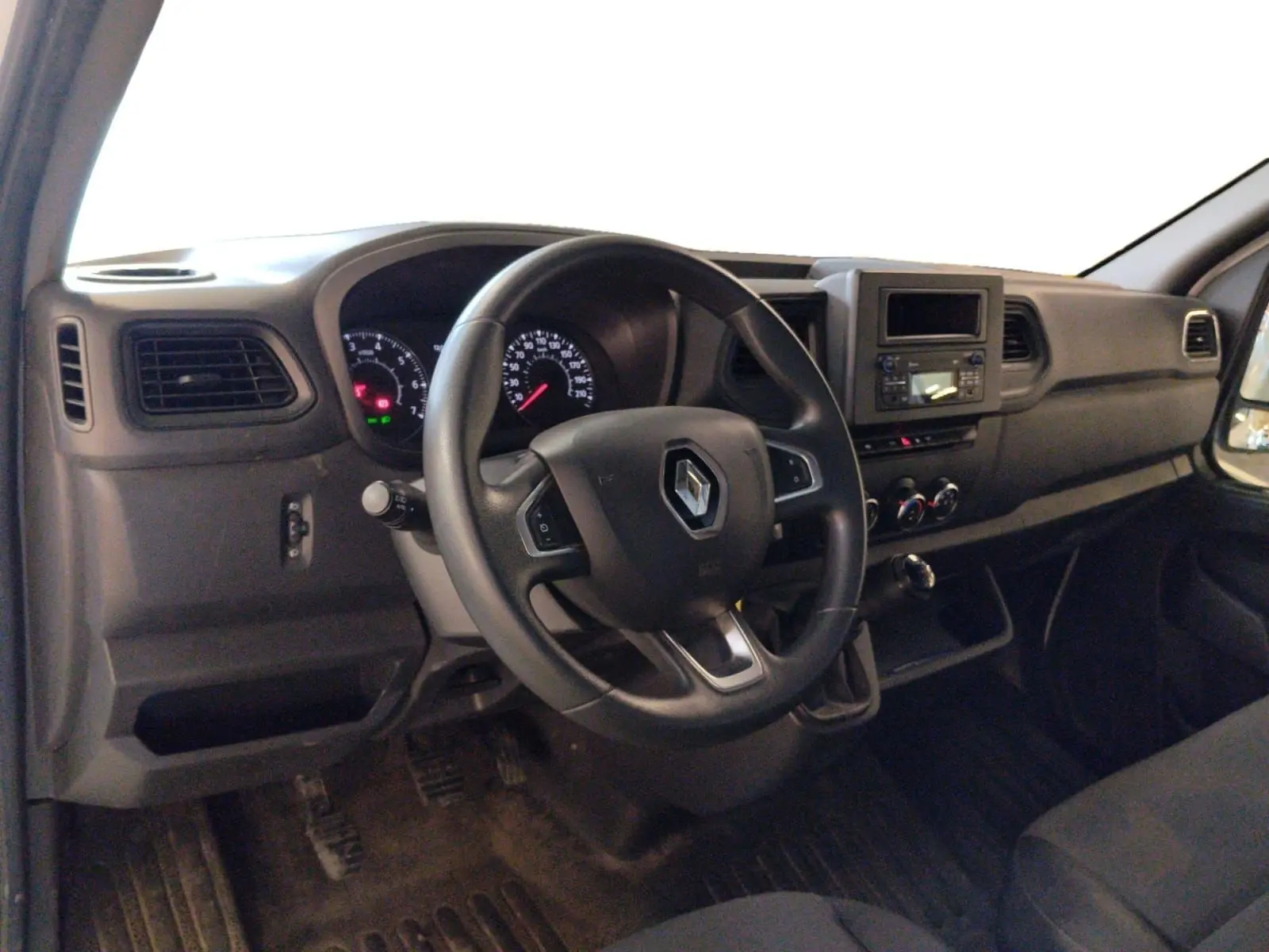 Vue intérieure côté conducteur du Renault Master 2023, tableau de bord noir avec volant multifonction et commandes visibles.
