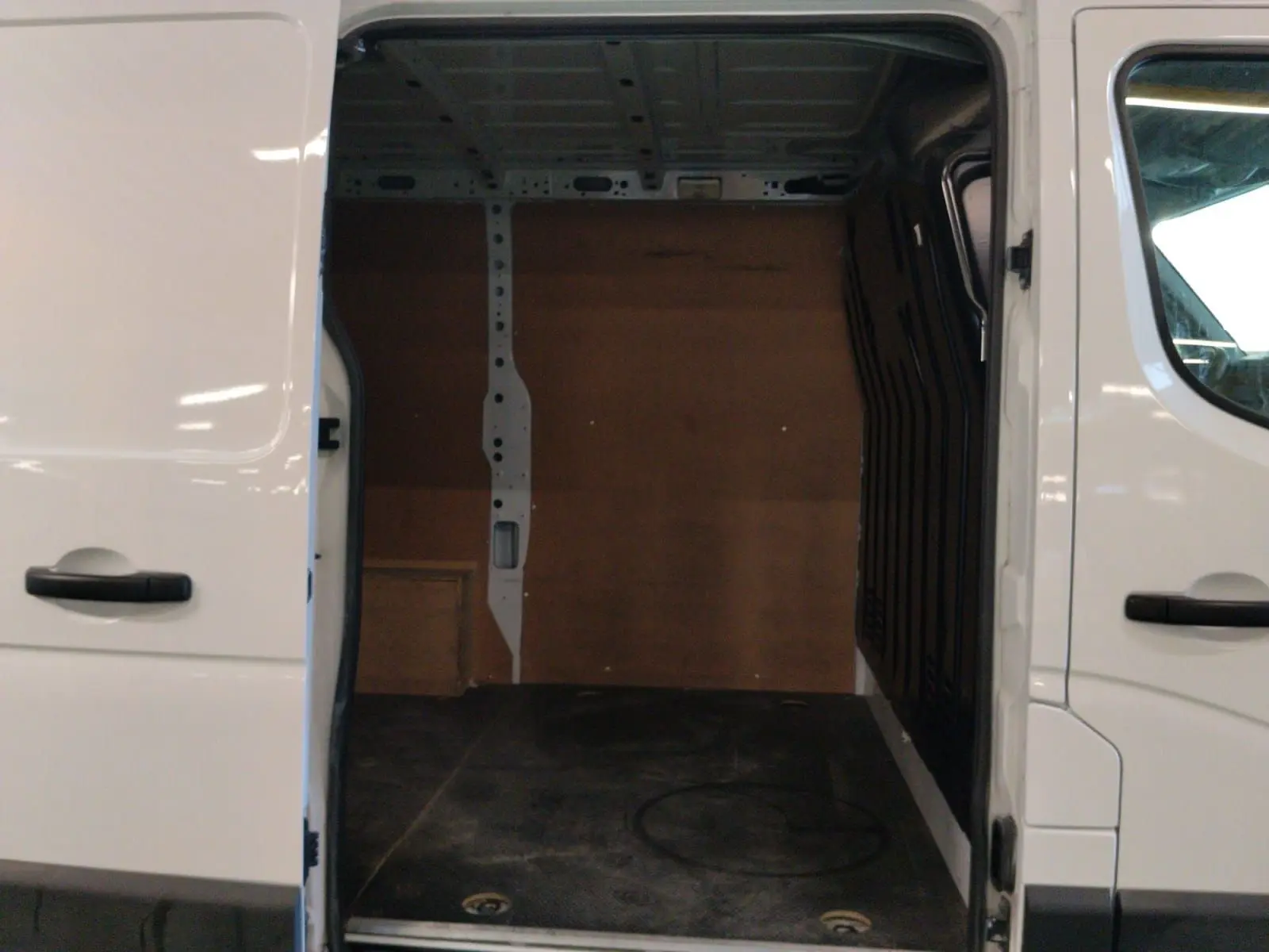 Vue de côté droit sur l’ouverture de la porte coulissante d’un Renault Master blanc 2023, montrant l’espace de chargement vide.