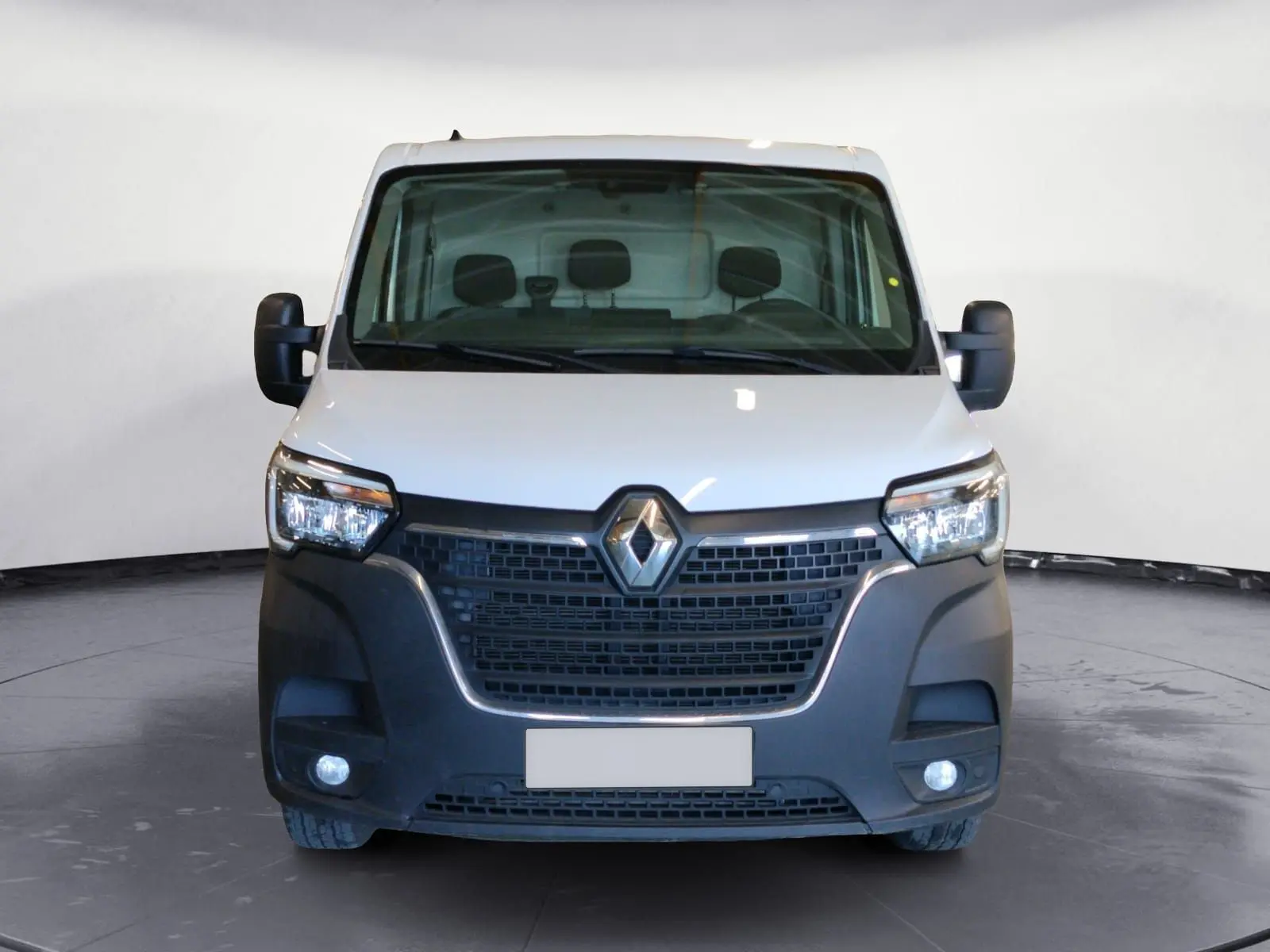 Vue frontale d’un Renault Master blanc 2023 avec calandre noire et feux allumés sur fond neutre.