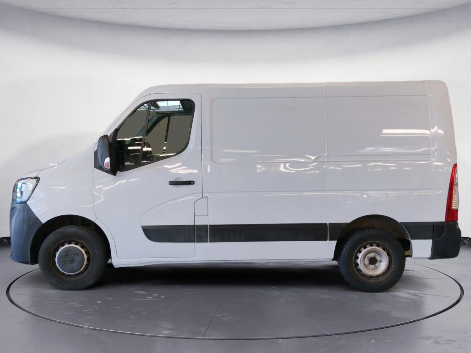 Vue latérale côté gauche d’un utilitaire Renault Master blanc L1H1 avec bande noire basse et porte coulissante fermée.