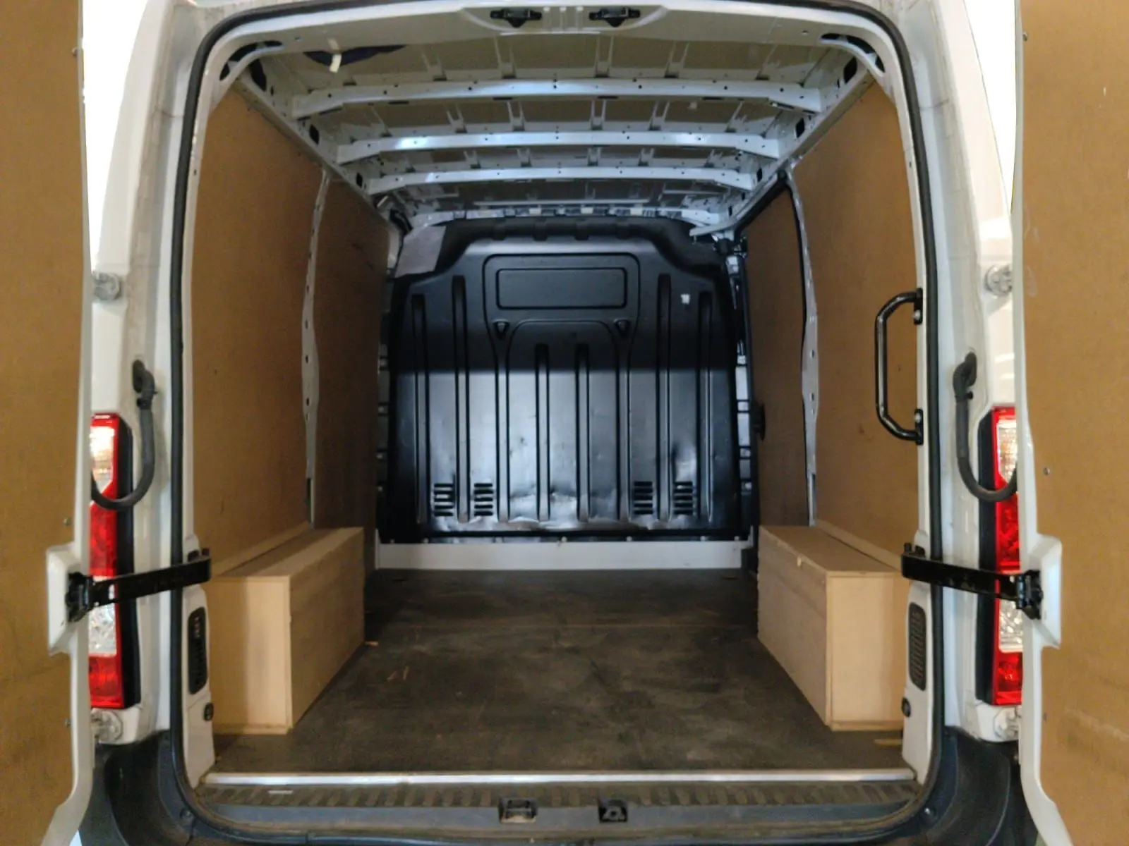 Vue arrière ouverte du Renault Master blanc 2023, montrant l’espace de chargement avec habillage bois et cloison noire.