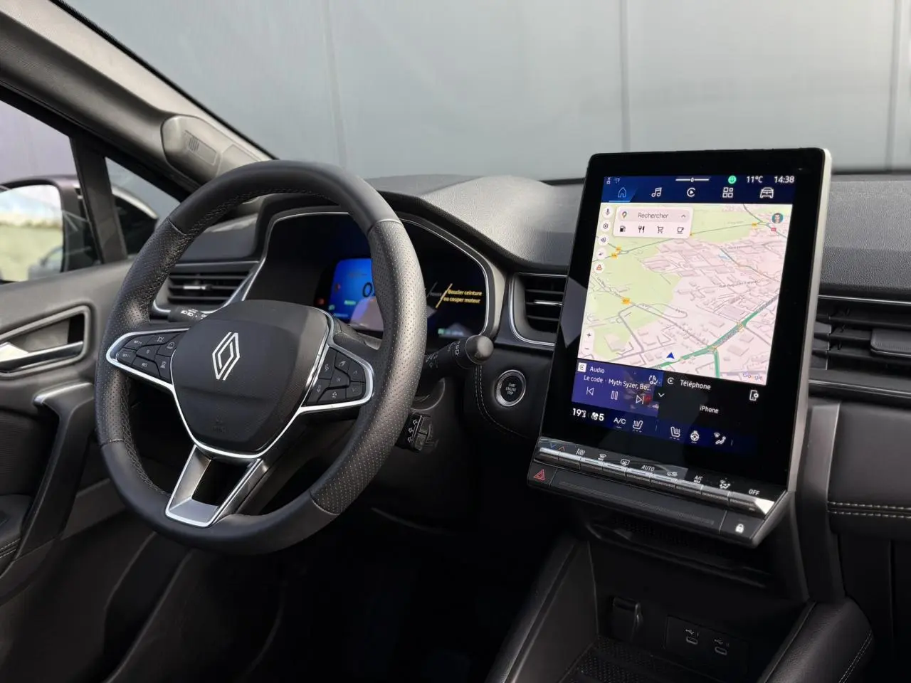 Vue intérieure du tableau de bord et volant noir de la Renault SYMBIOZ avec écran tactile vertical et commandes intégrées.