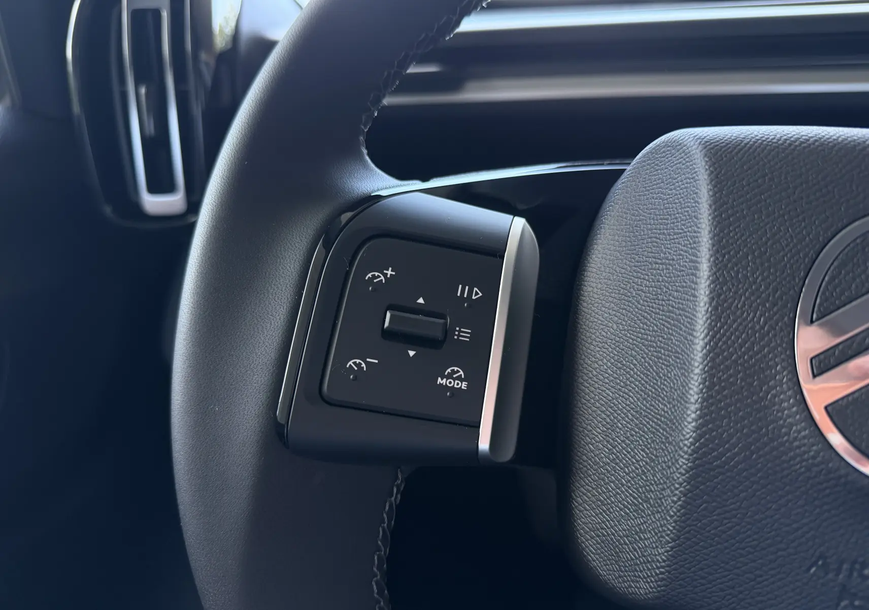 Gros plan sur les commandes du régulateur de vitesse à gauche du volant noir du Citroën E-C3 113 MAX 2025.