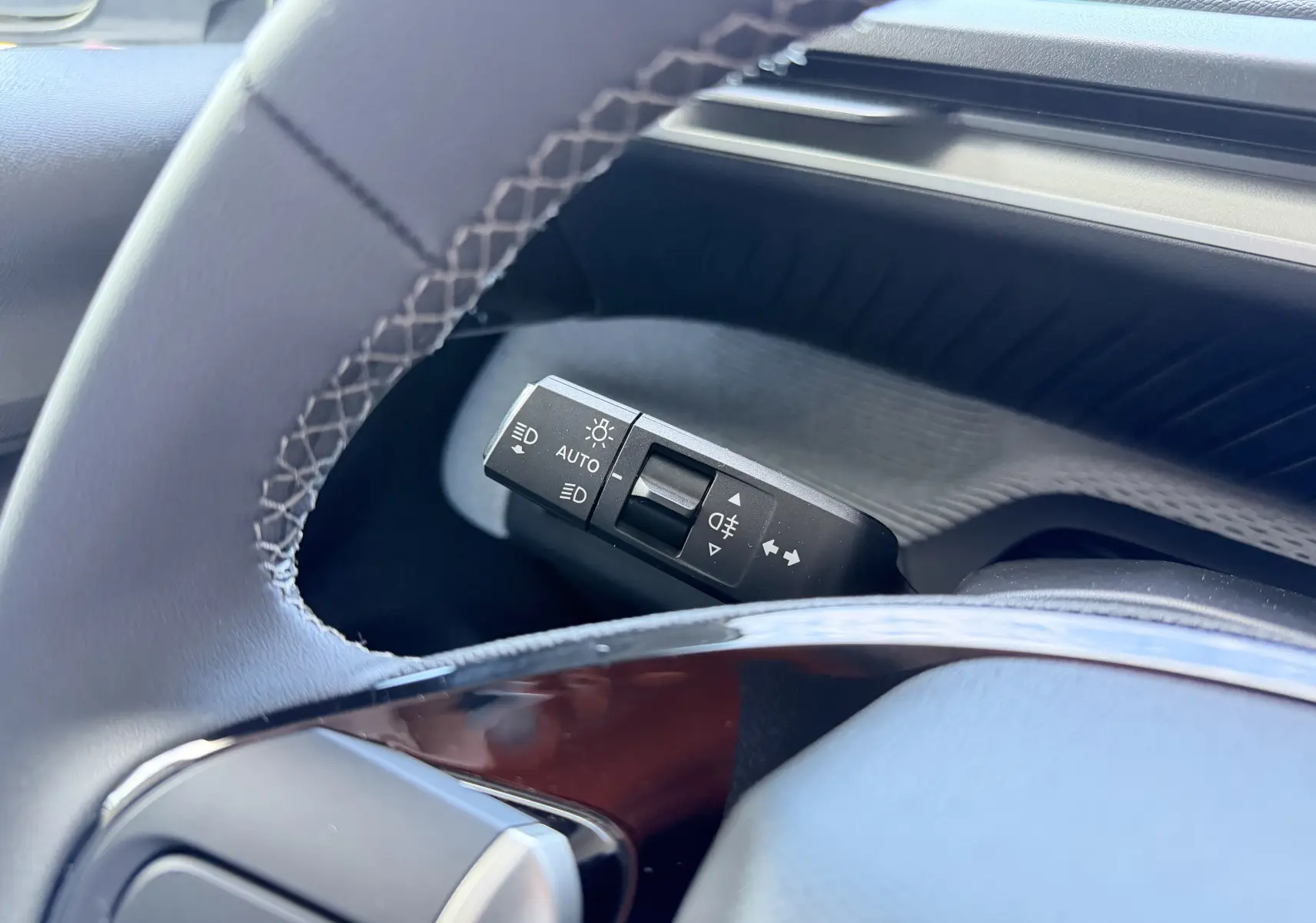 Gros plan sur la commande des feux au volant du Citroën E-C3 113 MAX 2025, intérieur noir et gris.