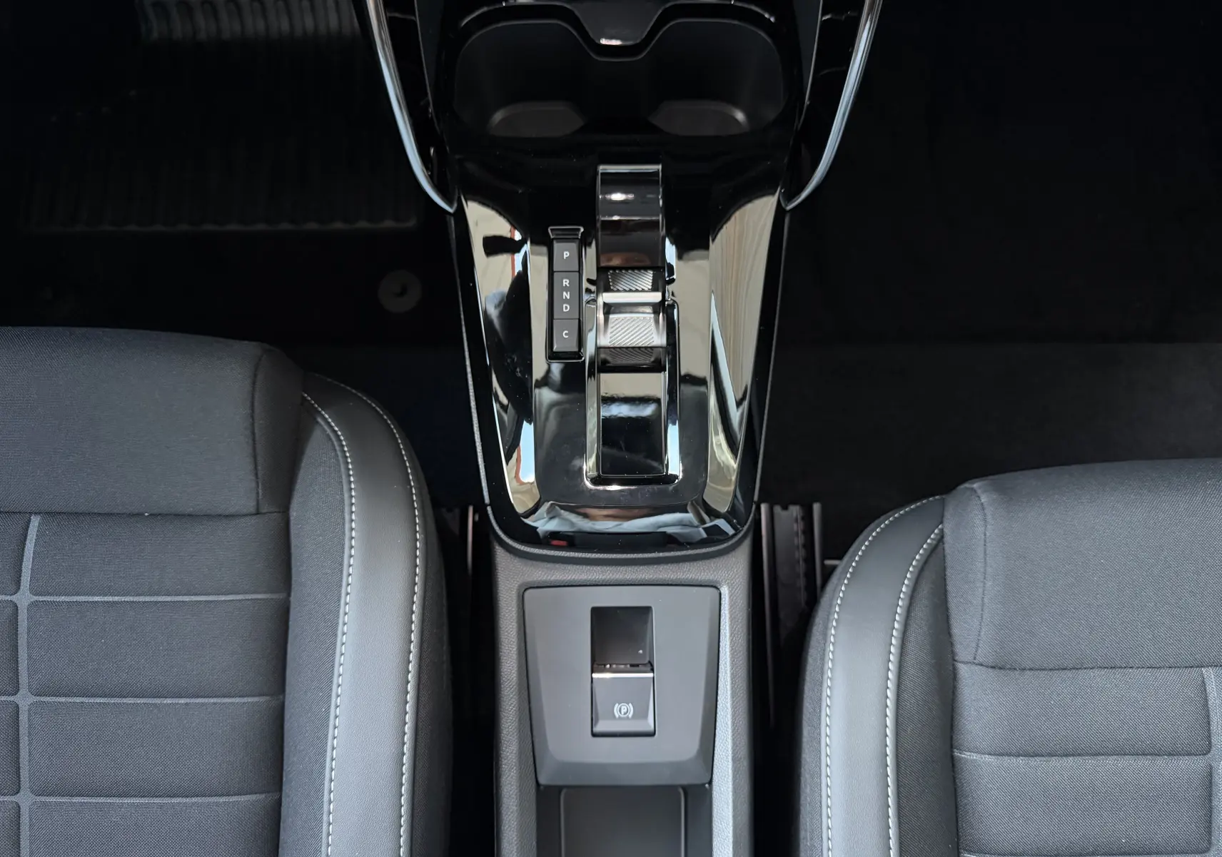 Vue plongeante sur la console centrale noire brillante et la sellerie tissu noir de la Citroën E-C3 113 MAX 2025.