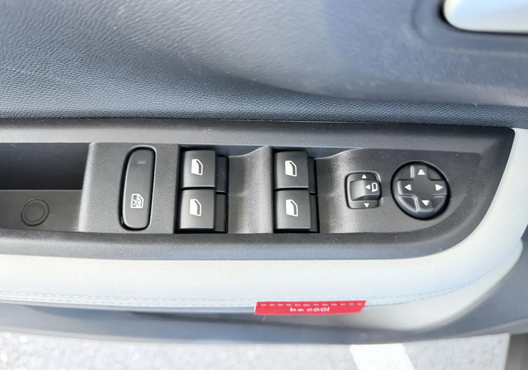 Gros plan sur les commandes des vitres et rétroviseurs côté conducteur de la Citroën E-C3 113 MAX gris Mercury.