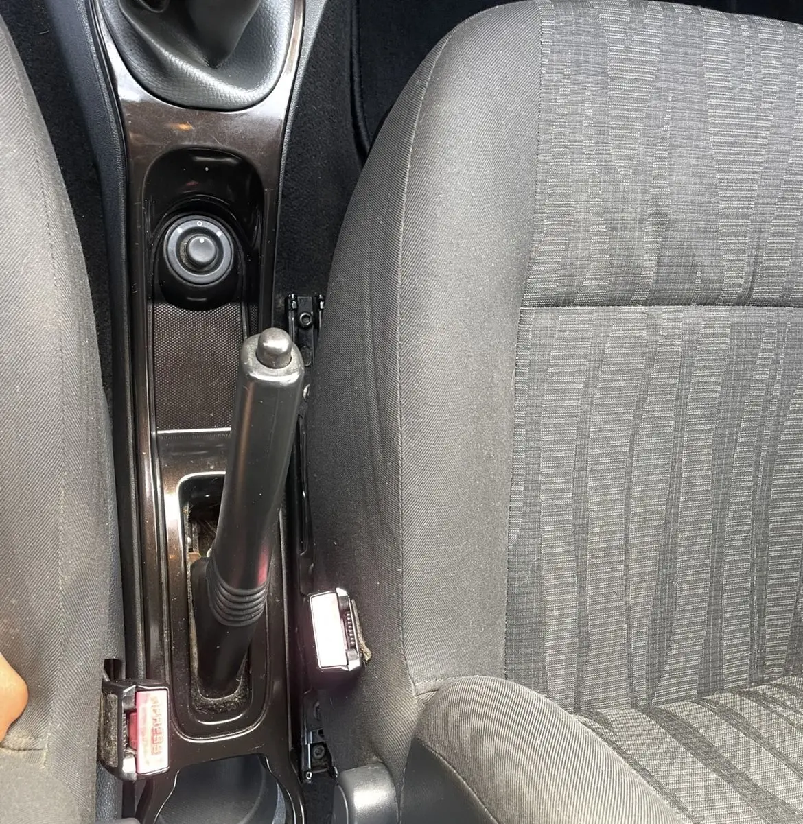 Vue rapprochée de la console centrale et des sièges avant gris du Dacia Duster 2011 avec frein à main manuel et levier de vitesses.