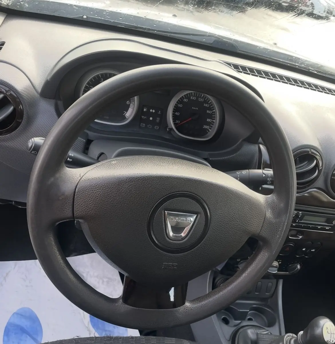 Vue intérieure centrée sur le volant et le tableau de bord du Dacia Duster 2011, avec levier de vitesse manuel visible.