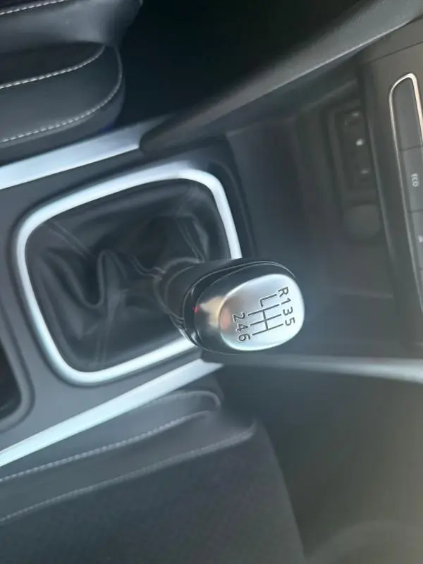 Gros plan sur le levier de vitesses manuel noir et argenté de la Renault Mégane IV gris clair, intérieur cuir noir.