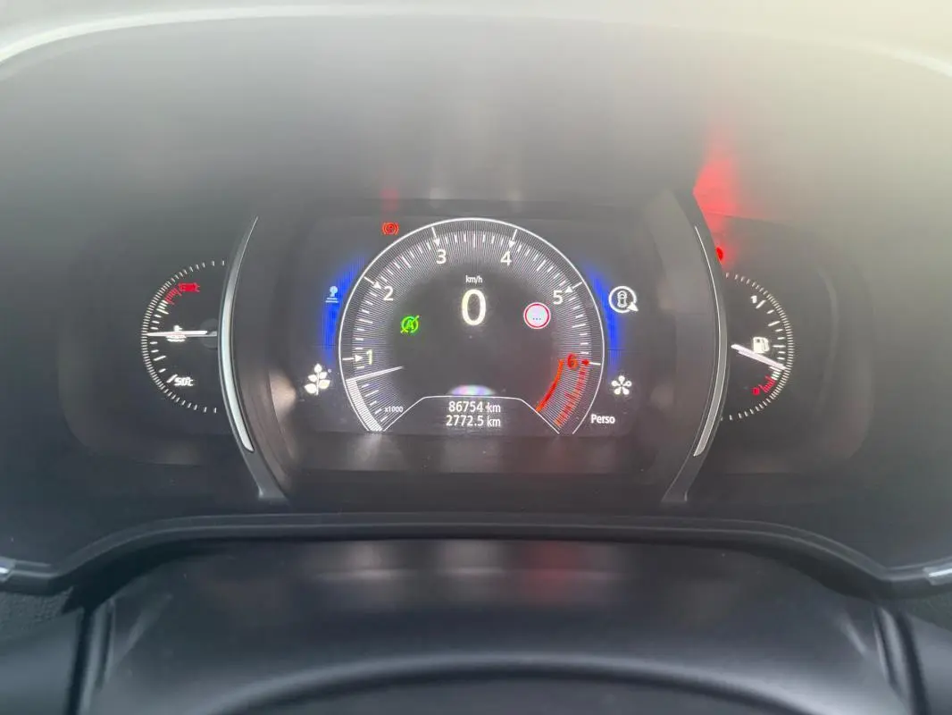 Tableau de bord numérique de Renault Mégane IV gris clair, affichant compteur et jauges avec éclairage bleu et rouge.