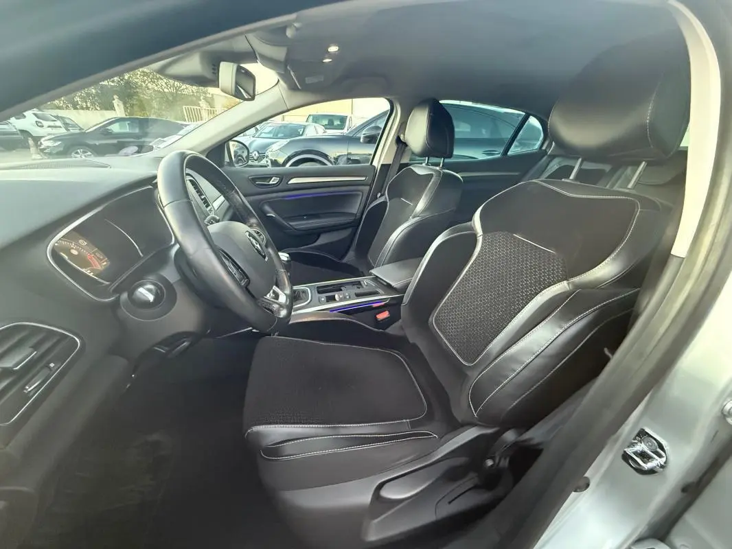 Intérieur de la Renault Mégane IV gris clair, vue côté conducteur montrant sièges sport en cuir et volant cuir.