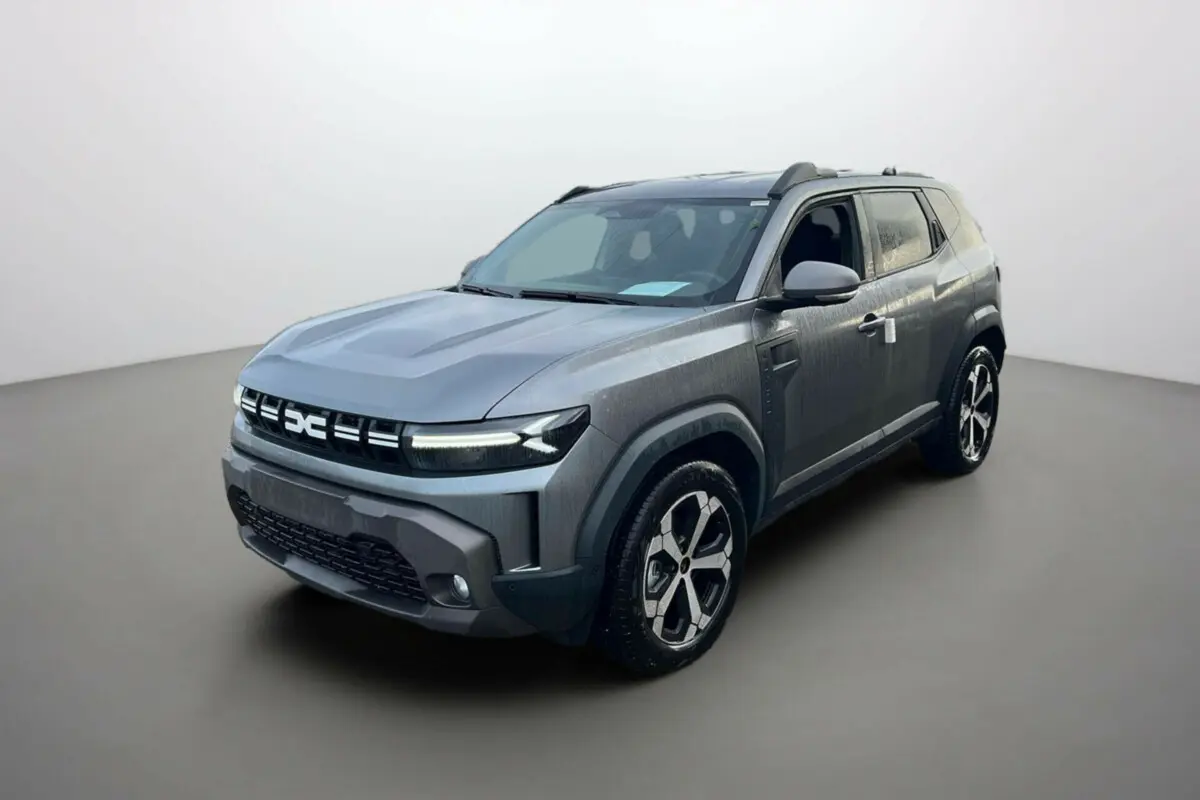 SUV Dacia Duster 2026 gris métallisé en 3/4 avant droit avec jantes alliage et barres de toit visibles