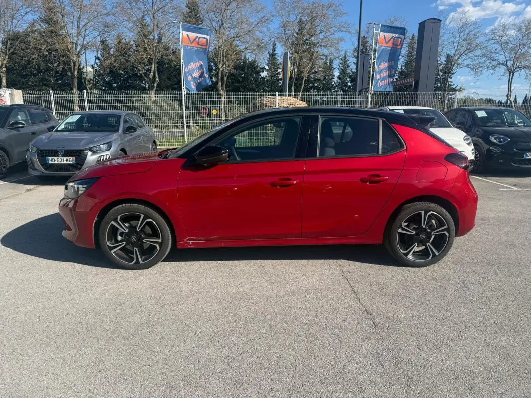 Opel Corsa 2025 rouge vue de profil côté gauche, avec jantes alliage noires et toit noir contrasté.
