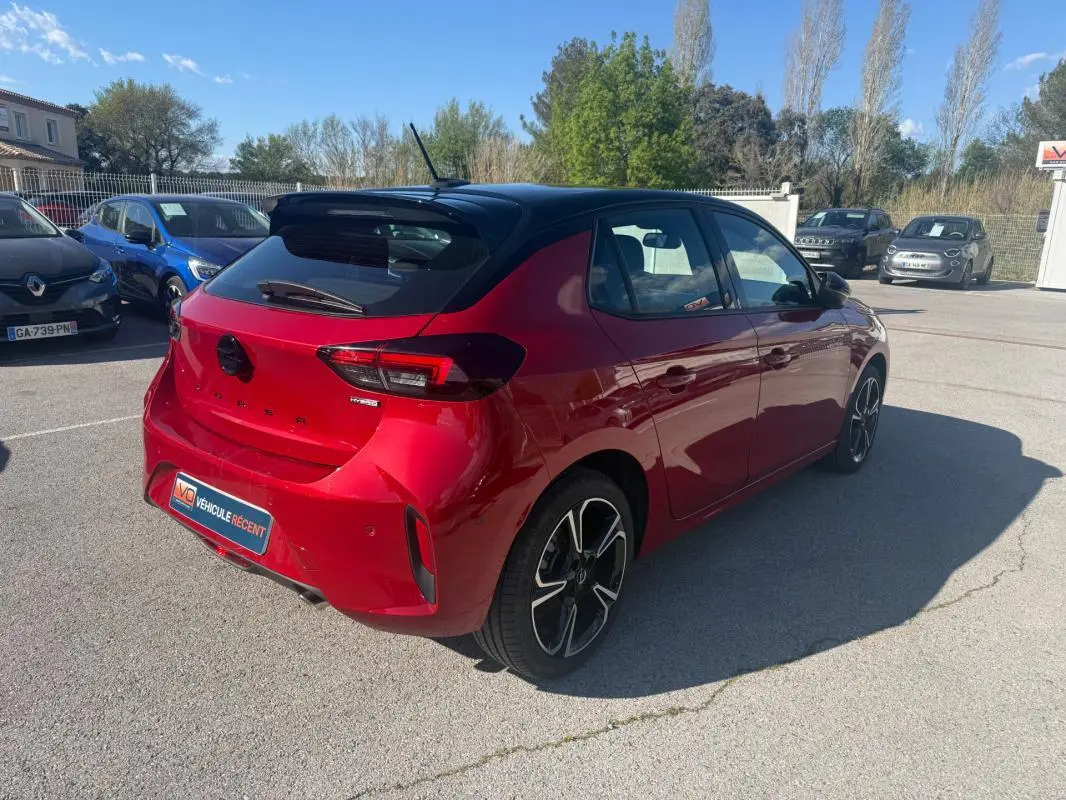 Vue 3/4 arrière droite de l'Opel Corsa rouge 2025 avec toit noir et jantes alliage distinctives.