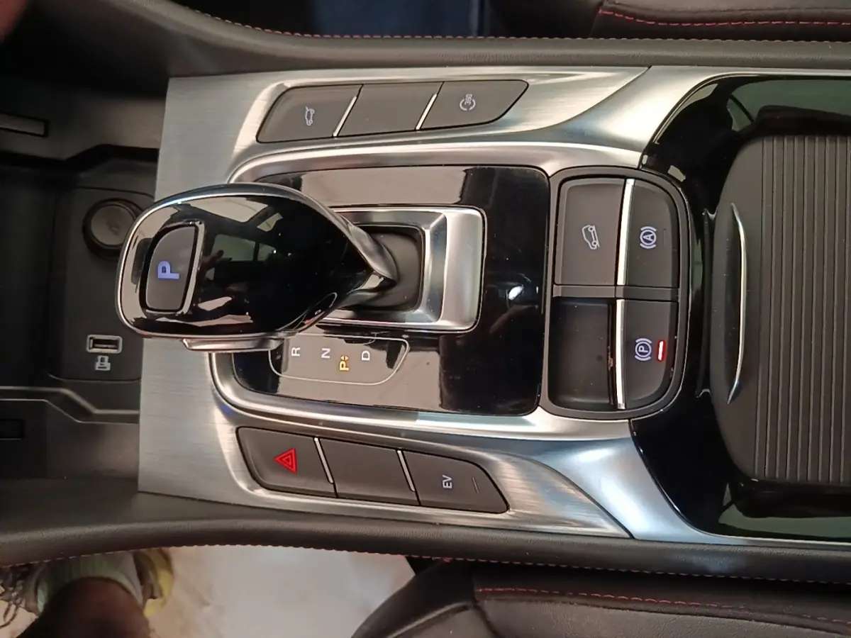 Gros plan sur la console centrale du MG Motor EHS blanc, avec levier de vitesse automatique et boutons de contrôle lumineux.