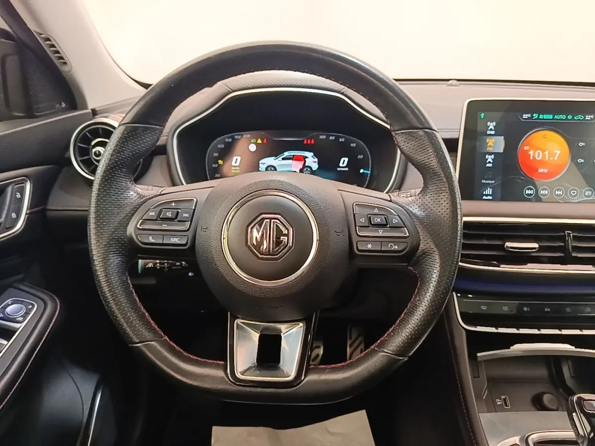 Vue intérieure centrée sur le volant cuir noir du MG Motor EHS 2023 avec tableau de bord digital et écran tactile couleur.