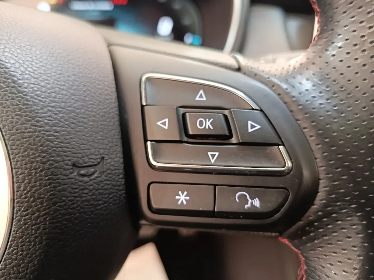 Gros plan sur les commandes multifonctions à droite du volant perforé du MG Motor EHS blanc, version 2023.