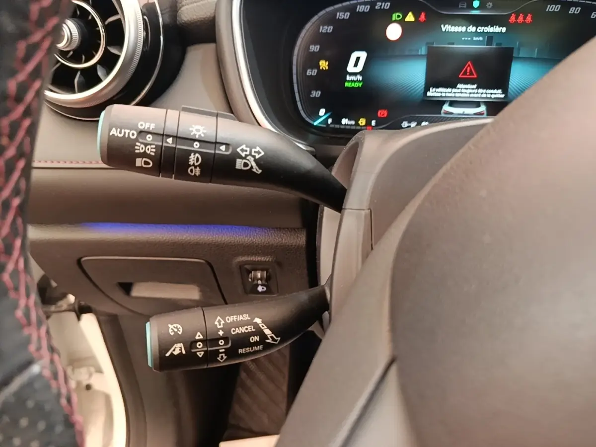 Gros plan sur le volant et les commandes de clignotants et régulateur de vitesse du MG Motor EHS hybride blanc, tableau de bord digital.