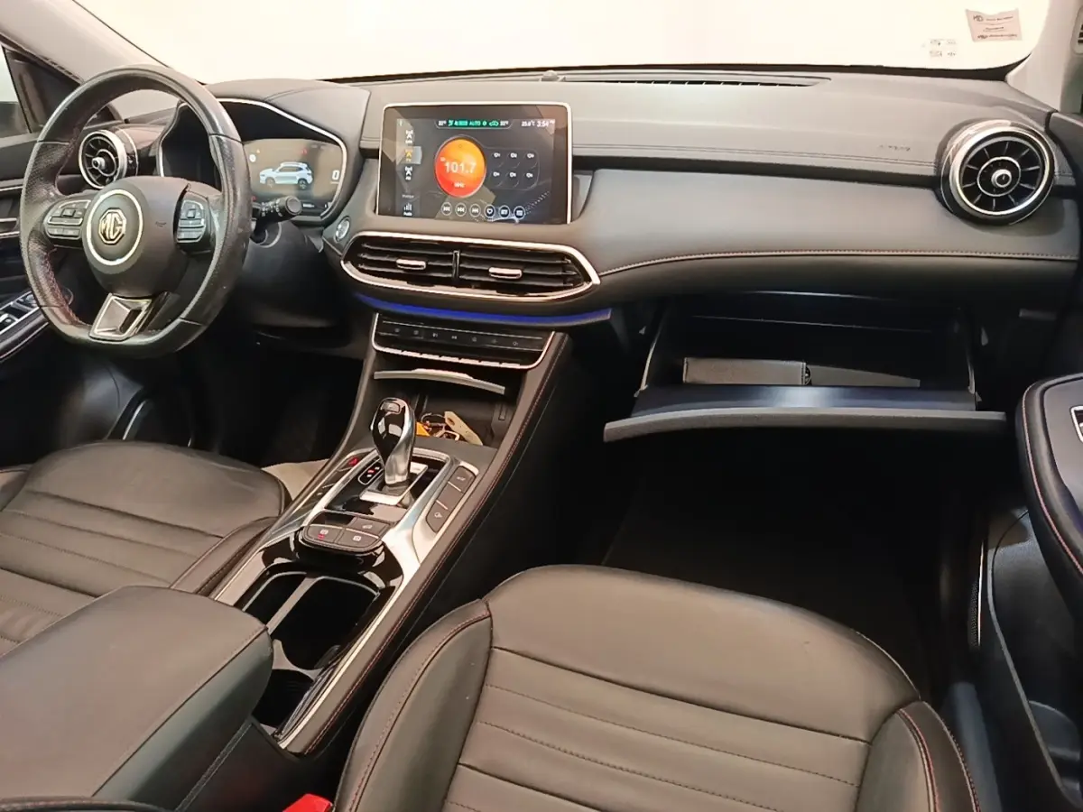 Vue intérieure avant du MG Motor EHS 2023, tableau de bord noir avec écran tactile central et volant multifonctions cuir.