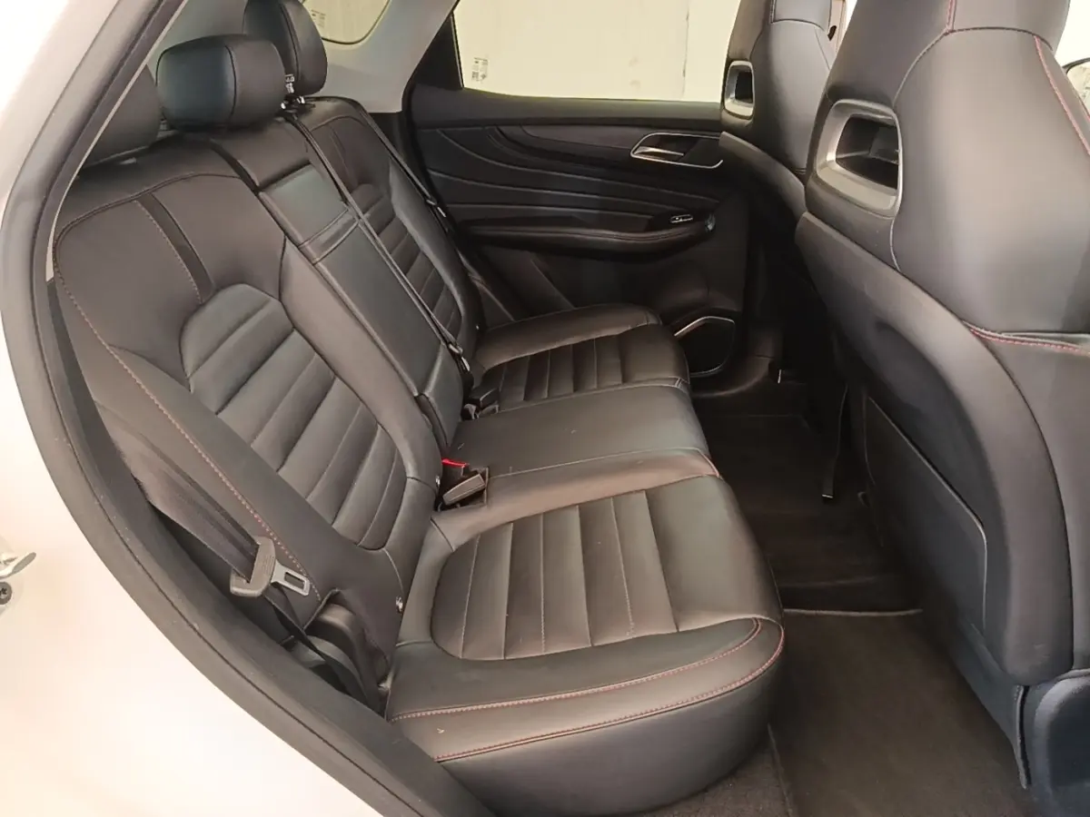 Vue intérieure arrière côté gauche des sièges en cuir noir avec surpiqûres rouges du MG MOTOR EHS hybride rechargeable blanc.