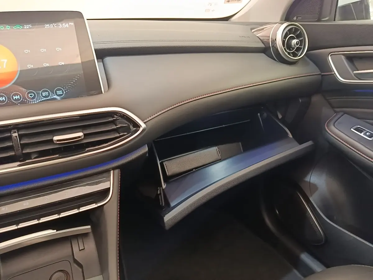 Intérieur côté passager du MG Motor EHS blanc 2023, tableau de bord noir avec boîte à gants ouverte et écran tactile visible.